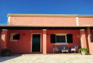 una casa roja con mesa y sillas en Amaryllis Boutique Apartments en Moraitika