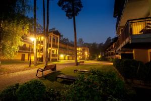 a park with benches and buildings at night at Natura Resort in Pogorzelica