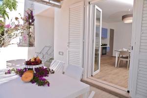 a white dining room with a table with flowers on it at Altomare Case Vacanza in Porto Cesareo +11 photos