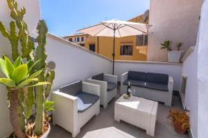 a patio with chairs and an umbrella on a balcony at Made in Ortigia Apartments in Syracuse