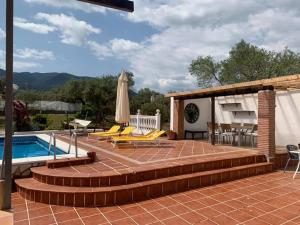 een patio met een zwembad en een terras met stoelen en een parasol bij Finca Casa Mici in Alhaurín el Grande