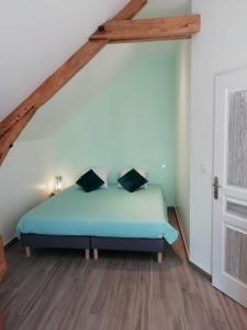 een slaapkamer met een blauw bed op een zolder bij Le Cottage de L Abbaye in Lonlay-lʼAbbaye