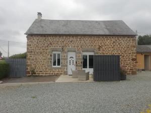a small brick building with a white door at Le Cottage de L Abbaye in Lonlay-lʼAbbaye