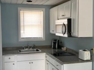 a kitchen with white cabinets and a sink and a window at Ocean Walk Hotel in Old Orchard Beach