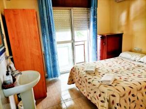 a bedroom with a bed and a sink and a window at AB Pension Granada in Granada