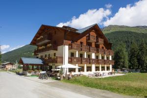 ein großes Gebäude mit Tischen und Stühlen davor in der Unterkunft Hotel Cevedale in Santa Caterina Valfurva