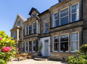 een oud stenen huis met een tafel en stoelen bij Wynnstay House in Harrogate