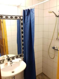 a bathroom with a sink and a blue shower curtain at Vikaneset Havhotell in Kristiansund