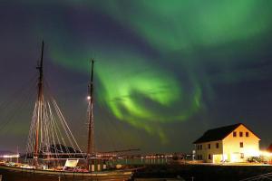 un barco atracado en un puerto bajo la aurora boreal en Vikaneset Havhotell en Kristiansund