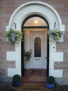 a white door with two potted plants on it at Strome Lodge in Inverness
