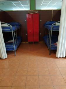 セーにあるAlbergue O Bordónの二段ベッド3組と赤いキャビネットが備わる客室です。