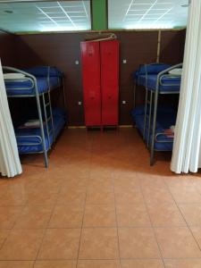 Pokój z 3 łóżkami piętrowymi i czerwoną szafką w obiekcie Albergue O Bordón w mieście Cee