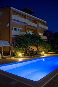 una piscina frente a un edificio por la noche en Apartments Bene, en Rab