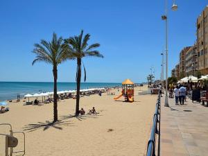 una spiaggia con palme e un parco giochi di Apartamento Bajo 3 Dúplex Marjal playa centro de Guardamar a Guardamar del Segura