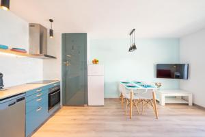 une cuisine avec des placards bleus et une table avec des chaises dans l'établissement Apartment Sofia, à L'Escala
