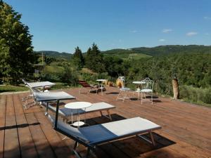 eine Gruppe von Tischen und Stühlen auf einer Holzterrasse in der Unterkunft B&B CASAGRANDE in Quercegrossa