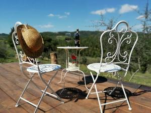 2 chaises et une table avec un chapeau sur la terrasse dans l'établissement B&B CASAGRANDE, à Quercegrossa