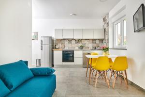 Una sala de estar con un sofá azul y sillas amarillas. en Apartmani Ivana, en Umag