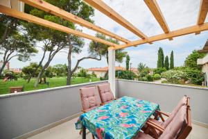 a porch with two chairs and a table and a pergola at Apartmani Ivana in Umag