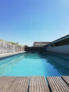 uma piscina de água azul com um deque de madeira em B&B De Vlaschaerd em Heule