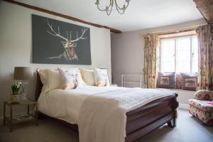 a bedroom with a large bed with a deer painting on the wall at Forthay Bed and Breakfast in North Nibley