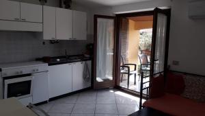 a kitchen with white cabinets and a door to a patio at appartamento La Palma in Posada