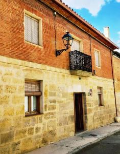- un bâtiment en briques avec un balcon et une porte dans l'établissement Casa Rurales Antigua Casa del Relojero, à Astudillo