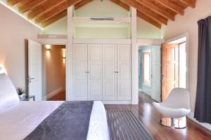 1 dormitorio con 1 cama grande y 1 silla blanca en Villa Allureh Emblematic Lodging, en Santa Lucía