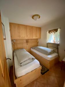 two beds in a room with wooden cabinets at Dolomites Charme Chalet in Colle Santa Lucia