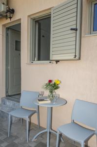 a table with two chairs and a vase of flowers at Tasos Rooms in Stoupa