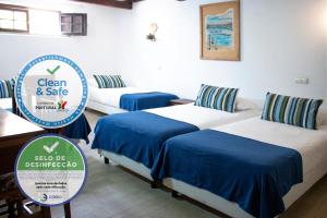 a room with three beds with a sign that says clean and safe at Rainha Santa Isabel - Óbidos History Hotel in Óbidos
