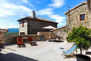 un patio con sillas y una sombrilla frente a un edificio en Rouretord La Rainette, en Gilhac-et-Bruzac