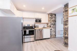 una cocina con electrodomésticos de acero inoxidable y armarios blancos en Modern Meets Rustic- 2 Bedroom in Old Quebec, en Quebec
