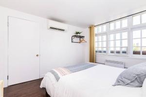 een witte slaapkamer met een bed en een raam bij Modern Meets Rustic- 2 Bedroom in Old Quebec in Québec