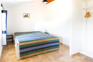 a bed in a white room with a colorful blanket at Rouretord La Rainette in Gilhac-et-Bruzac