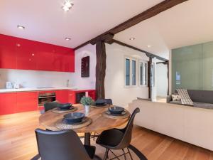 una cocina con armarios rojos y una mesa y sillas de madera. en Bilbao City Hall VI by Aston Rentals, en Bilbao