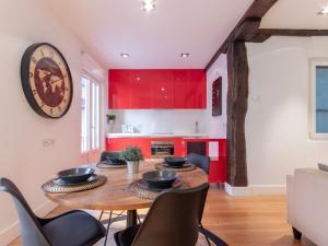 a kitchen with red cabinets and a wooden table and chairs at Bilbao City Hall VI by Aston Rentals in Bilbao