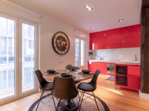 a kitchen with red cabinets and a wooden table and chairs at Bilbao City Hall VI by Aston Rentals in Bilbao