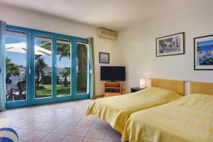 a bedroom with a bed and a tv and a balcony at Apartments Villa Ana in Medulin
