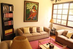 Hostal La Encantada في مدينة ميكسيكو: غرفة معيشة بها كنبتين ولوحة على الحائط