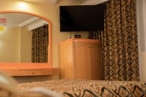 ein Schlafzimmer mit einem TV und einer Kommode mit einem Spiegel in der Unterkunft Hotel Atlante in Mexiko-Stadt