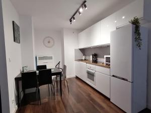 a kitchen with a table and a white refrigerator at Green Apartments Kraków in Kraków