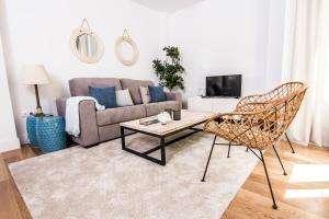 uma sala de estar com um sofá, uma mesa e cadeiras em Letmalaga Premium Malagueta em Málaga