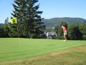 a man is playing golf on a golf course at Motel Chantmartin in Tadoussac