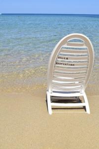 a white beach chair sitting on the beach at Battistina Holiday Home in Monte Nai