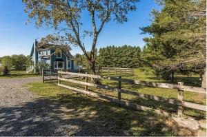 a wooden fence in front of a blue house at Lovely Lac-Brome 3 Bedroom Lakefront Cottage in Lac-Brome