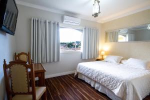 a bedroom with a white bed and a window at Hotel Nevada in Campos do Jordão