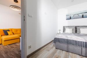 a bedroom with a bed and a yellow couch at Apartament MILAN Gardenia Dziwnów z widokiem na morze EPapartamenty in Dziwnów