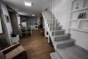 a staircase in a living room with a couch and a kitchen at Casiña Branca in Camariñas +2 photos