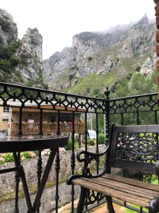 a bench on a balcony with a table and mountains at Posada La Cuadrona in La Hermida